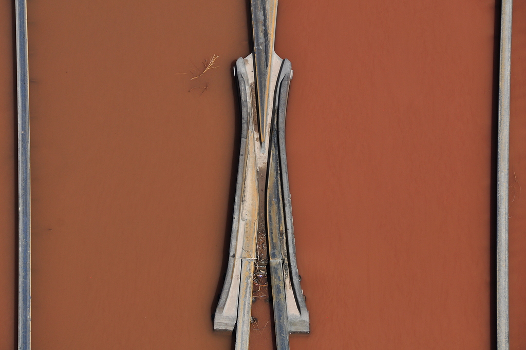 Intersecting rails surrounded by muddy water as seen from overhead.