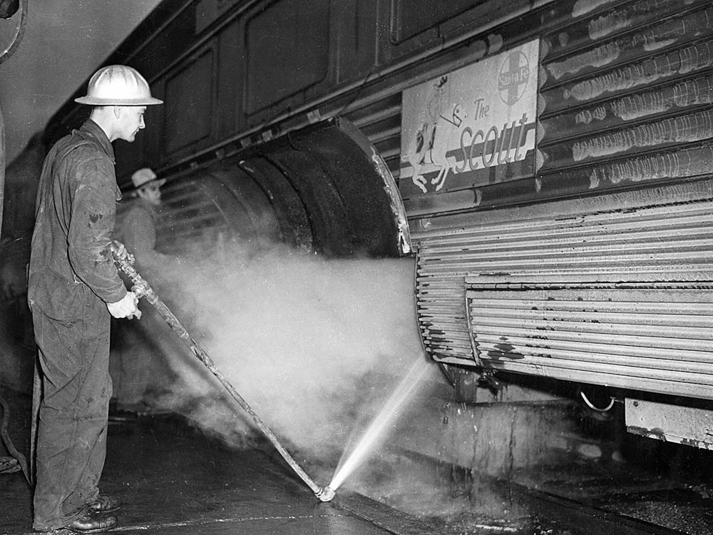 A worker cleans air conditioning equipment on a coach