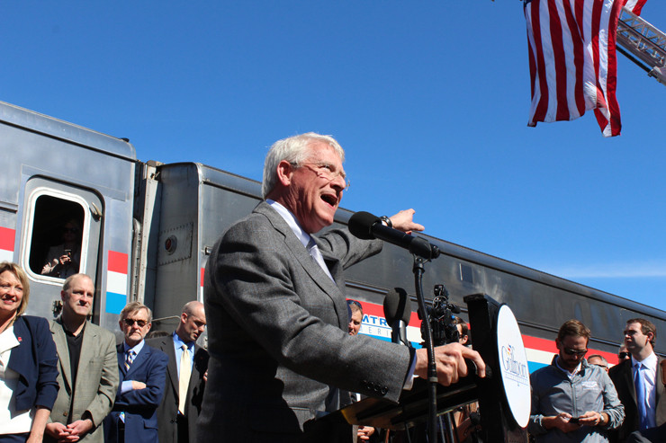 Man speaking to crowd in front of Amtrak train