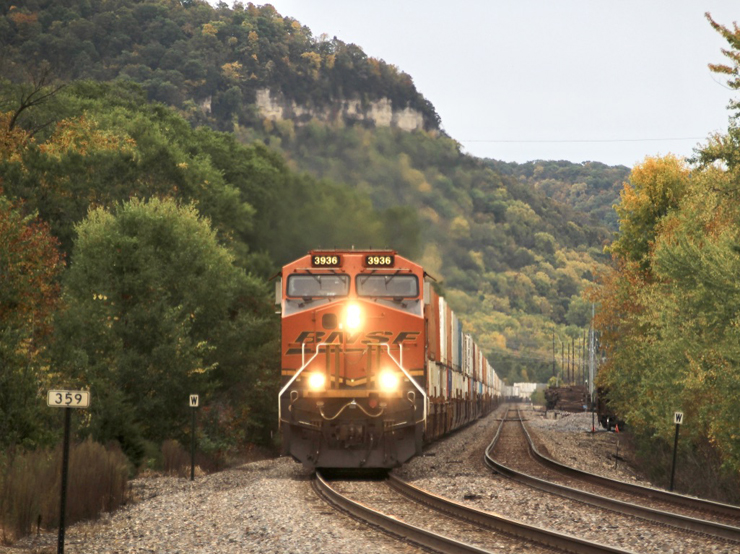 intermodal train approaches curve with bluffs as backdrop
