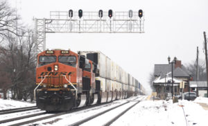 BNSF train passing signal bridge in snow