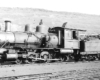 Old 4-6-0 steam locomotive shown in a rail yard.