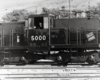 Center-cab diesel electric locomotive seen in at rest in a rail yard.