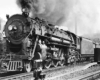 A steam locomotive appears with a train in a rail yard.