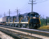 Four diesel locomotives coupled together haul a train on a multi-track main line.