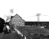 Two trains on separate, converging tracks appear in one view with a house like structure at the apex.