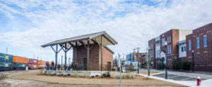 Brick pavilion between train tracks and downtown buildings