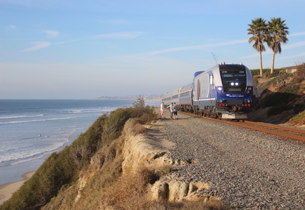 Passenger train running on hillside above Pacific Ocean