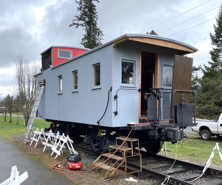 Gray wooden caboose under restoration