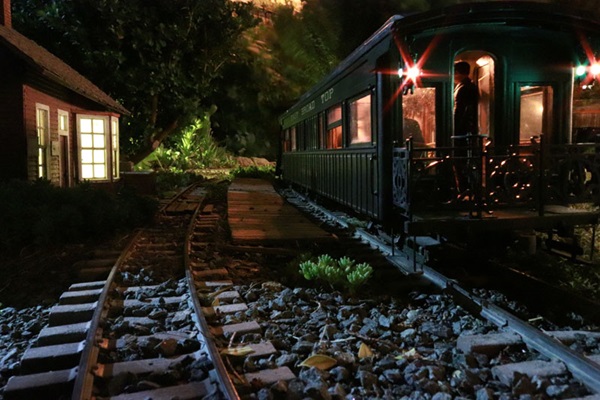 Nighttime trackside scene with lit station