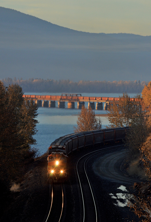 Train in shadows with bridge in distance
