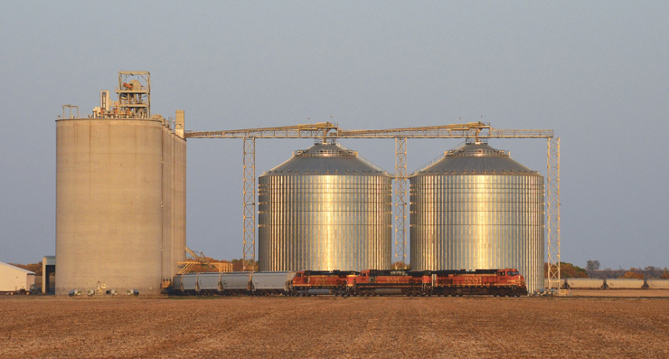 Freight train in front of large grain silos