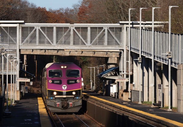 Commuter train passes under pedestrian bridge
