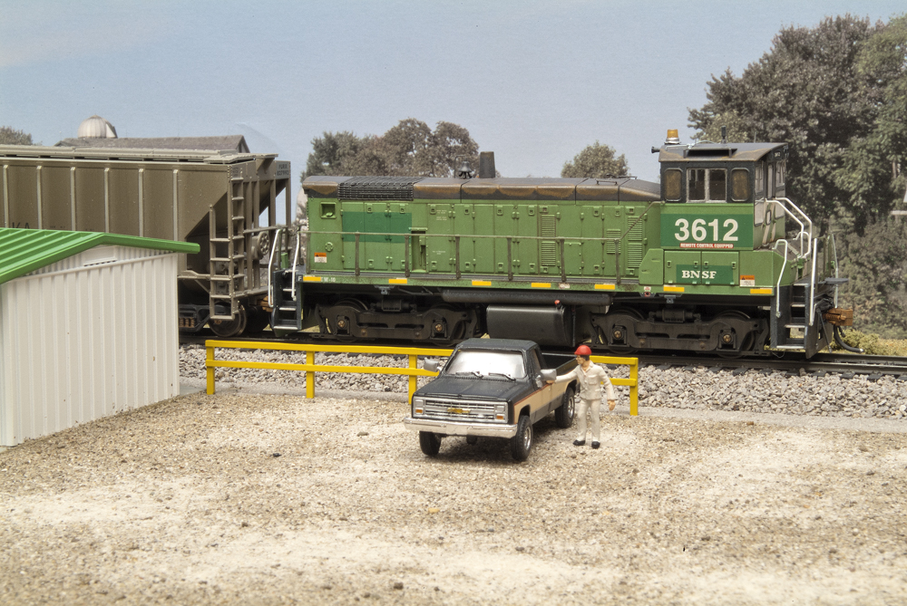 Central Valley HO scale fence painted yellow in a yard office scene with BNSF SW1000 no. 3612 and pickup truck.