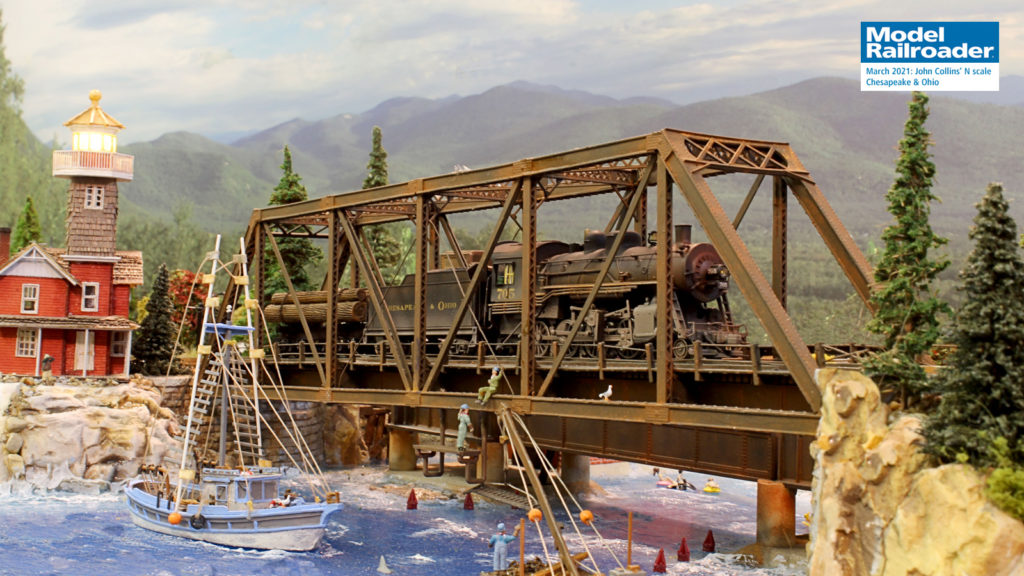 A steam locomotive crosses a steel trestle above a harbor bobbing with fishing boats