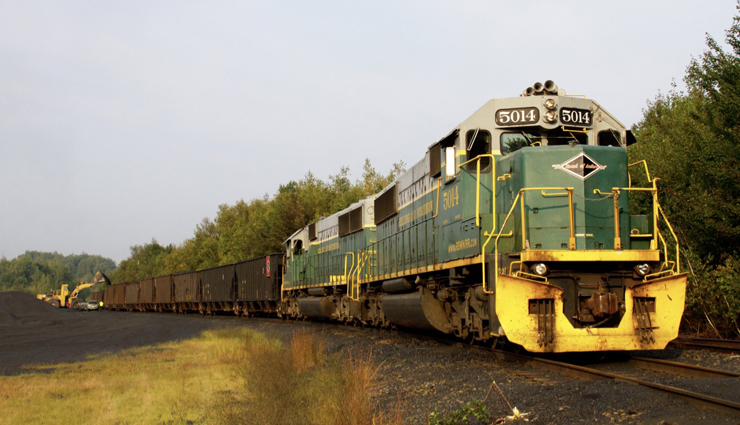 Green and yellow locomotives on train of hopper cars