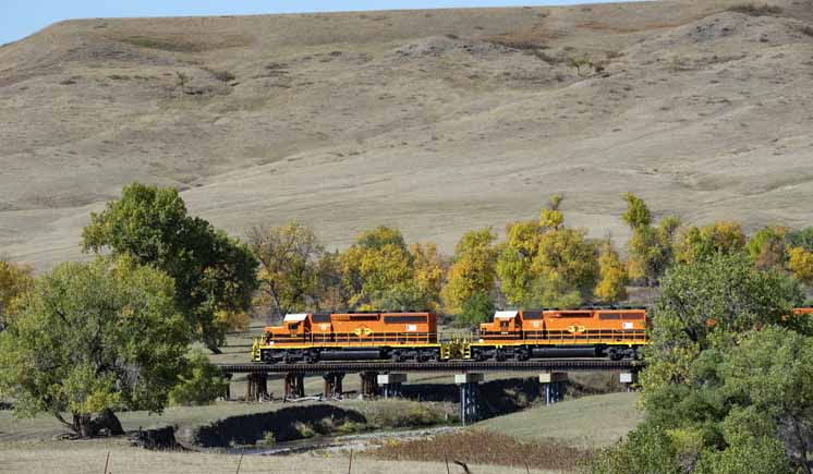 Orange diesel locomotives on low trestle in valley