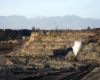 A steam locomotive hauls a short train through a mined area.