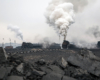 Loose lump coal in the fore ground frames two steam locomotives in an industrial rail yard.