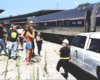 A helmeted worker speaks to gathered people in front of a train.