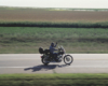 Motorcycle rider waiving while driving.