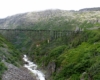 Decrepit wood and steel bridge perched over frothy mountain stream.