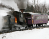 A cog railway steam locomotive emitting steam and smoke.