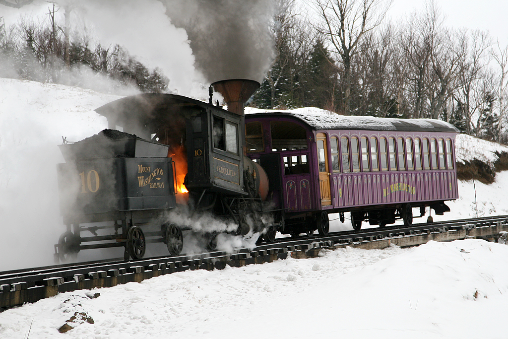 Cog steam locomotive with a passenger car on a steep incline.