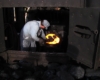 Railroad worker shovels coal lumps into a steam locomotive firebox.