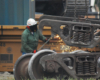 Railroad worker with torch creating sparks with a freight car truck.