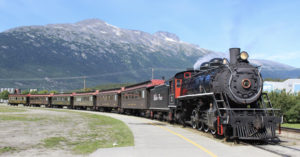 Steam locomotive on passenger train in front of mountains