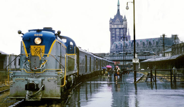 Diesel powered passenger train in station wit big stone tower