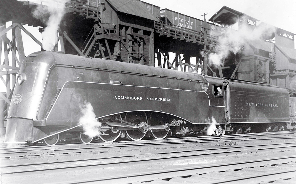 Black-and-white streamlined steam locomotive in a rail yard.