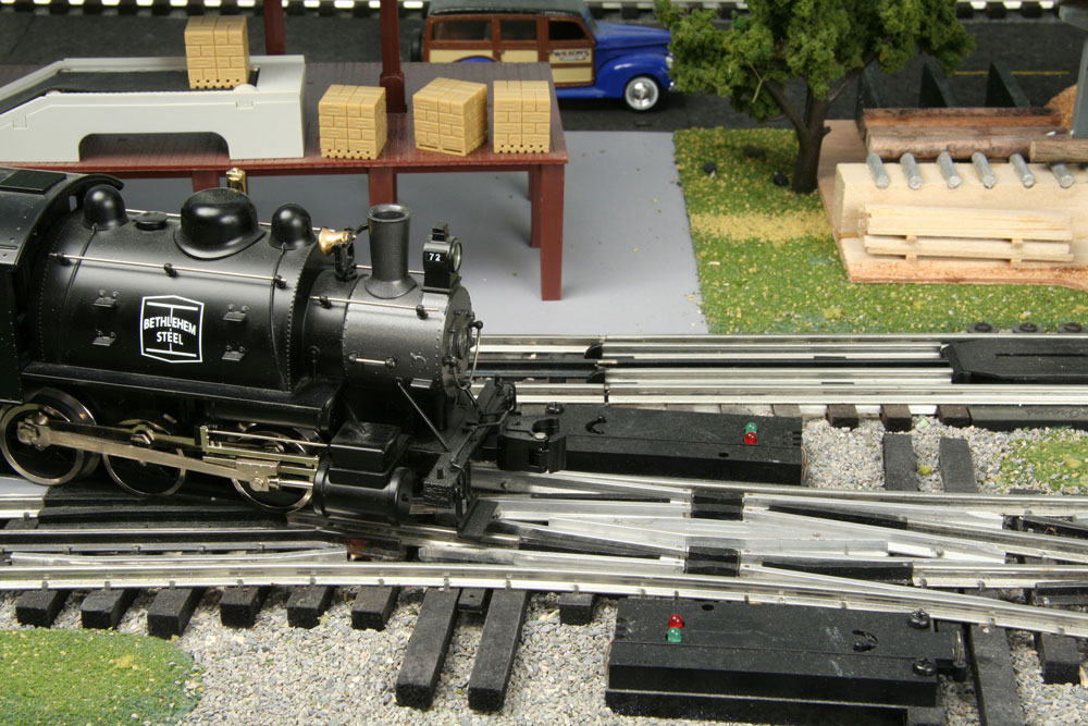 A short O gauge 0-6-0t steam switcher approaches a pair of track turnouts