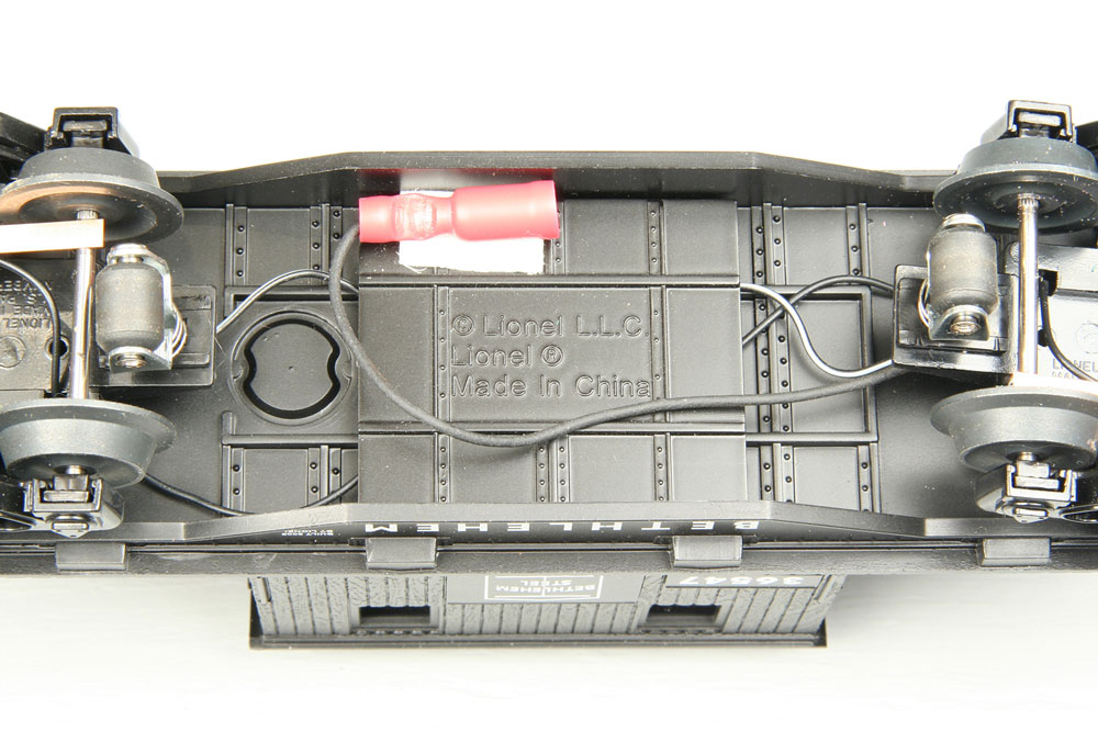 Truck reattached to caboose body with wired female connector affixed to the underside with a piece of double-sided tape in a position that does not show when caboose is on track.