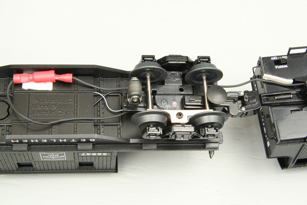 The underside of the locomotive and caboose coupled together with connected male and female solderless connectors.