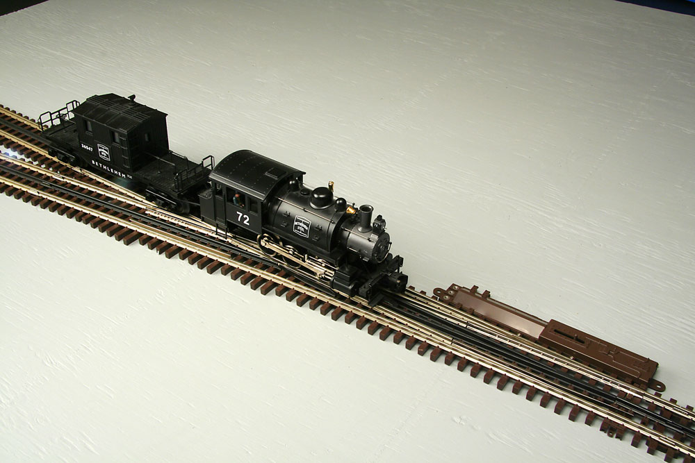 Locomotive and caboose upright on track approaching track switch.