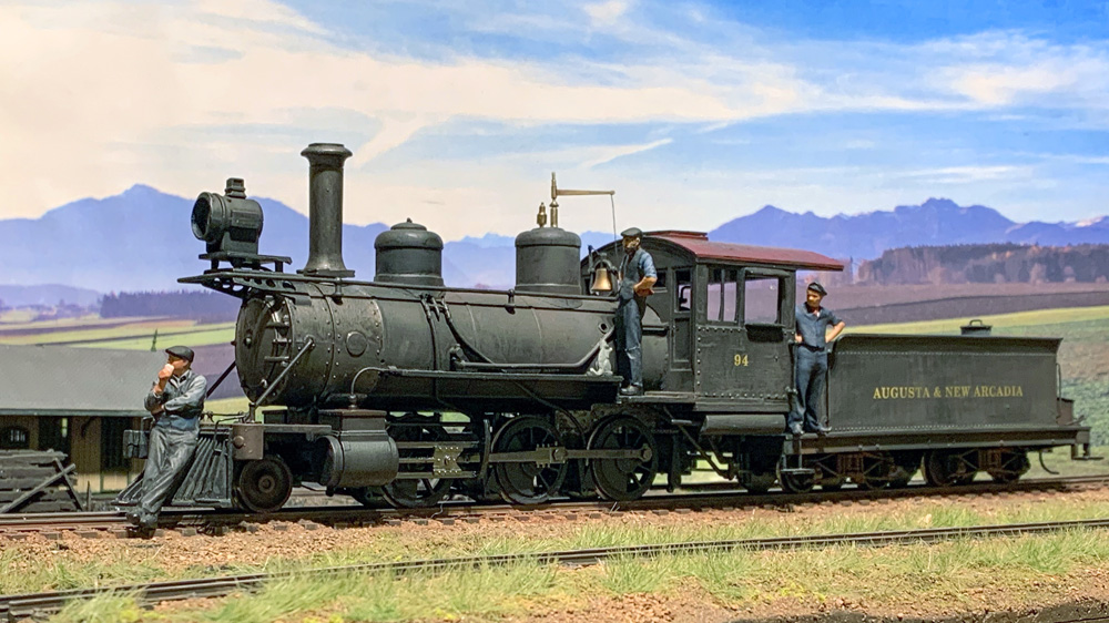 Three crew members stand around a 2-6-0 steam engine