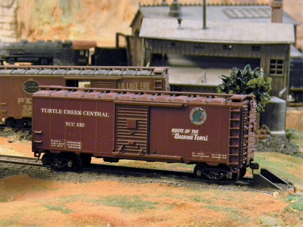 A brown steel boxcar lettered for the Turtle Creek Central RR, a fictional railroad, sits on a spur track
