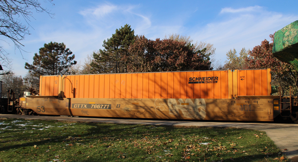A single orange shipping container in an intermodal well car.