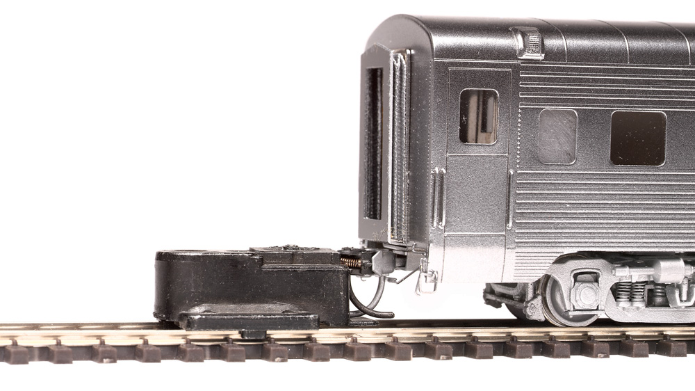 The height of a knuckle coupler on an HO scale passenger car is checked with a Kadee gauge.