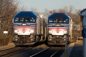 Two blue and silver commuter trains pass in station