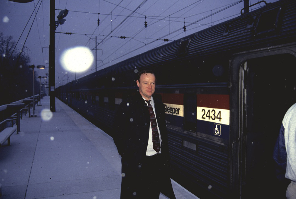 Attendant on platform outside train at night in snow