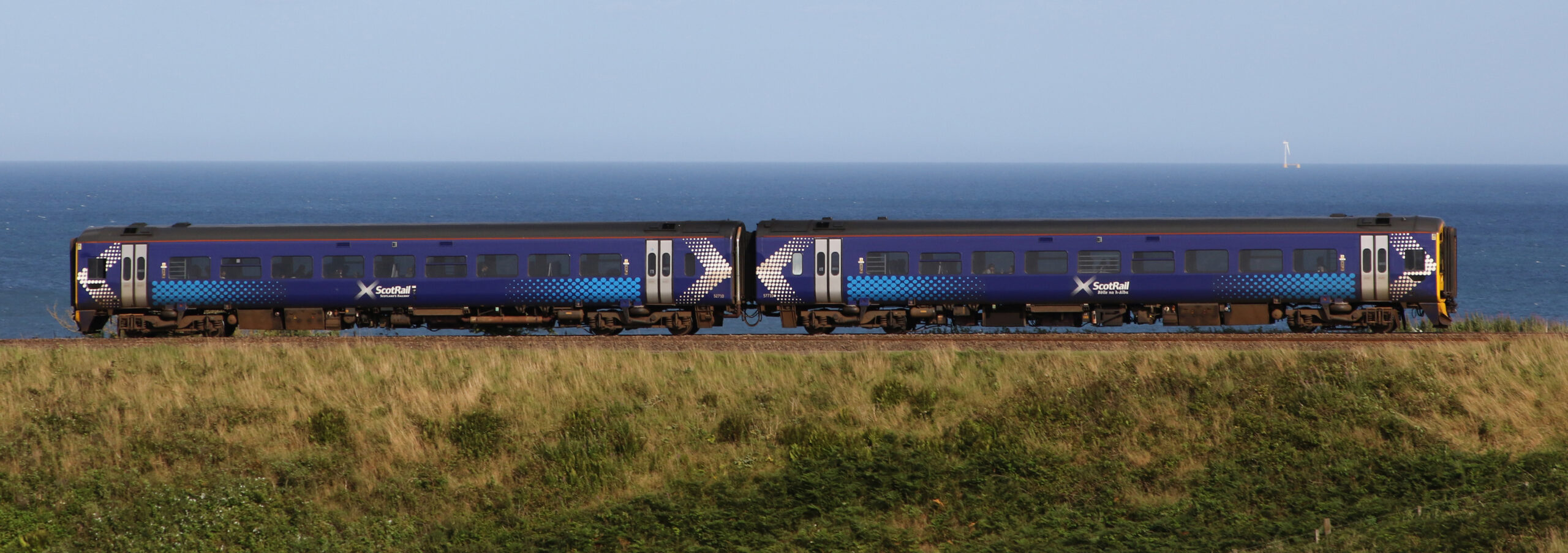 Two-car train running along shoreline