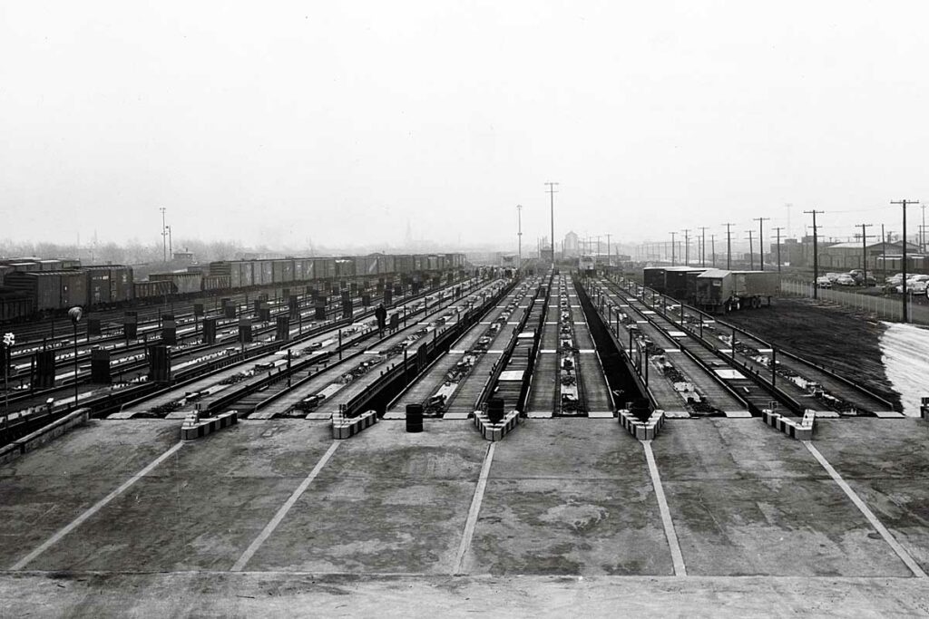 Flat cars lined up to load with semi trailers in yard