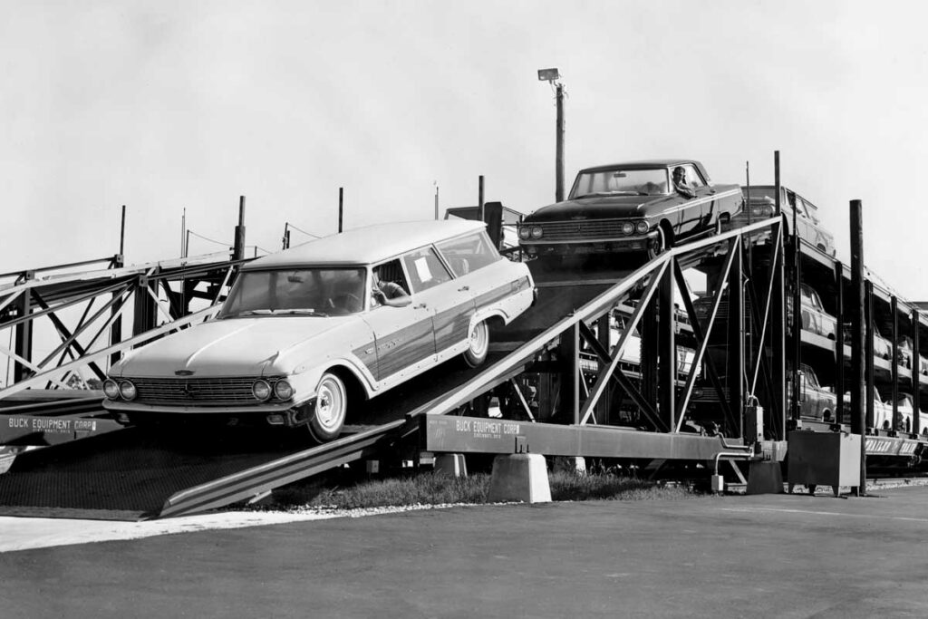 New automobiles are driven down a ramp off a railroad car