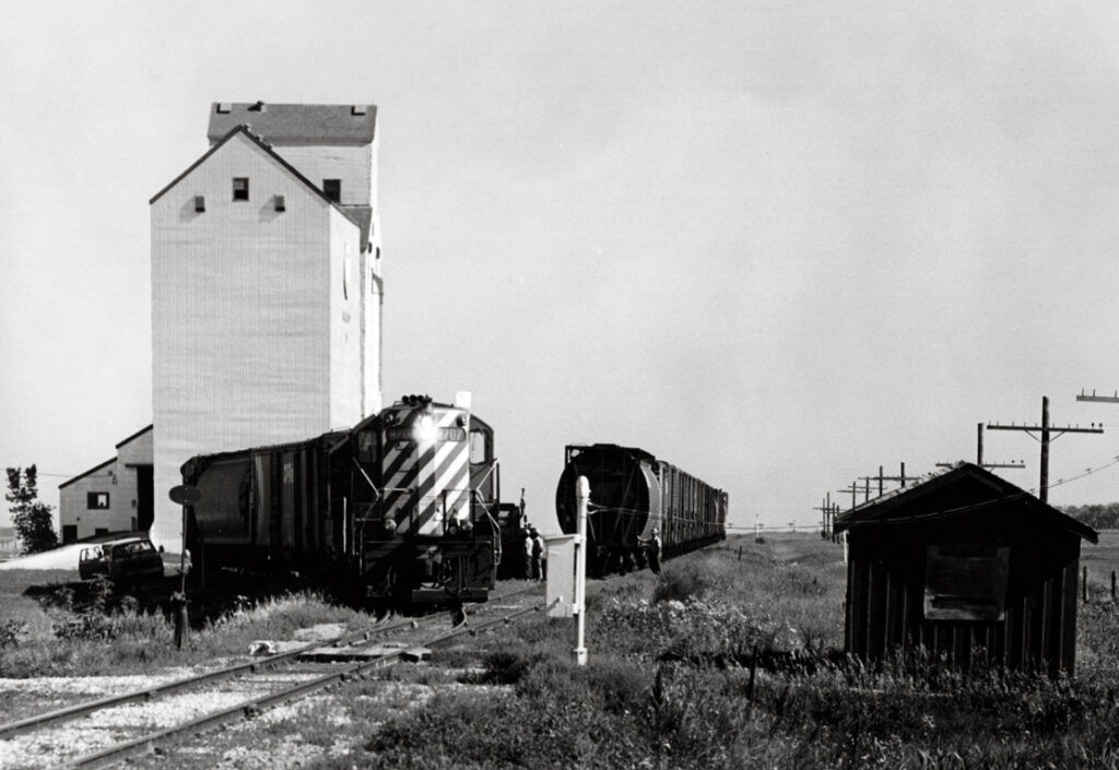 Diesel powered freight train switches cars at wooden grain elevator