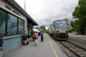 Diesel locomotive reflected in window of station with passenger on platform