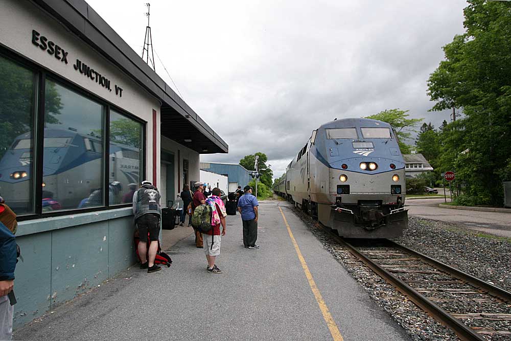 Diesel locomotive reflected in window of station with passenger on platform