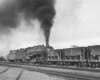 Steam locomotive pushing on rear of freight train